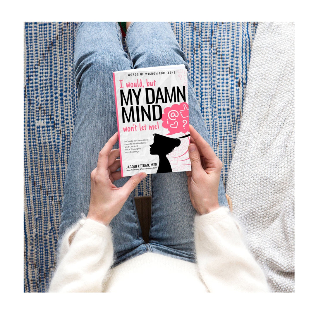 Top edge of the paperback teen girl book showing textured purple cover with subtle embossed title details and a glimpse of