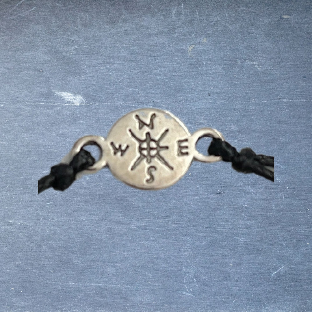 Close-up of the Pinky Promise Bracelet's silver compass charm with engraved details, showcasing intricate metalwork and