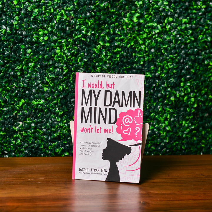 Close-up of the teen girl's paperback book cover showing vibrant pink and purple lettering with textured matte finish in