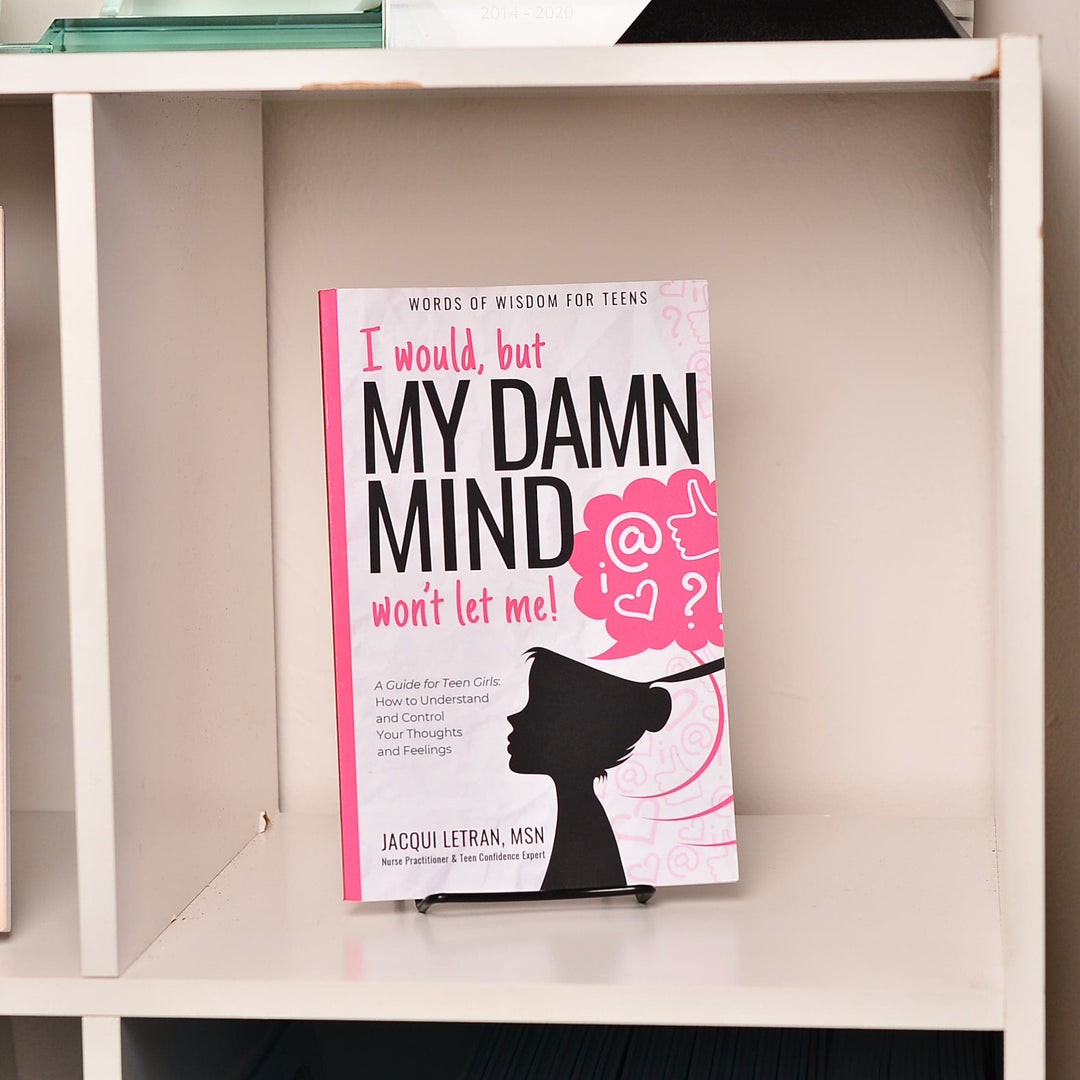 Close-up of the paperback book’s textured cover with vibrant pink and purple hues, showing a slight bend at the corner for a