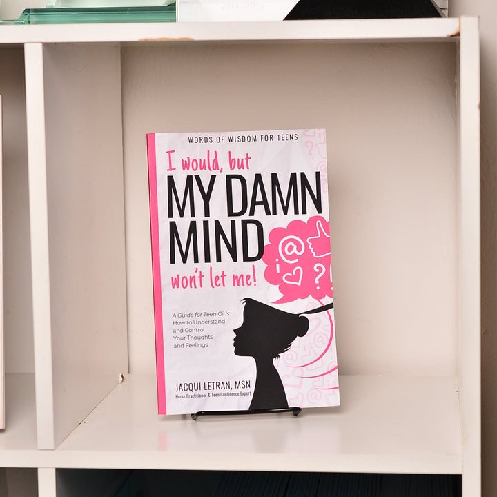 Close-up of the paperback book’s textured cover with vibrant pink and purple hues, showing a slight bend at the corner for a