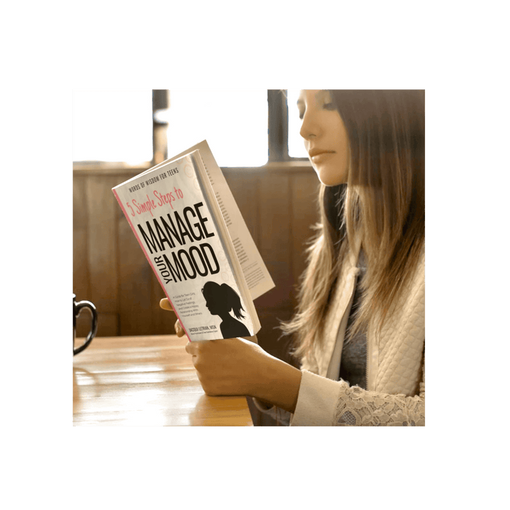 Close-up of the paperback’s textured cover featuring teal and pink typography, showing the book’s thickness and matte finish.