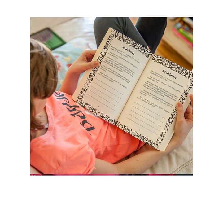 Close-up of the journal’s textured pastel pink cover with embossed floral accents and a gold foil title label.