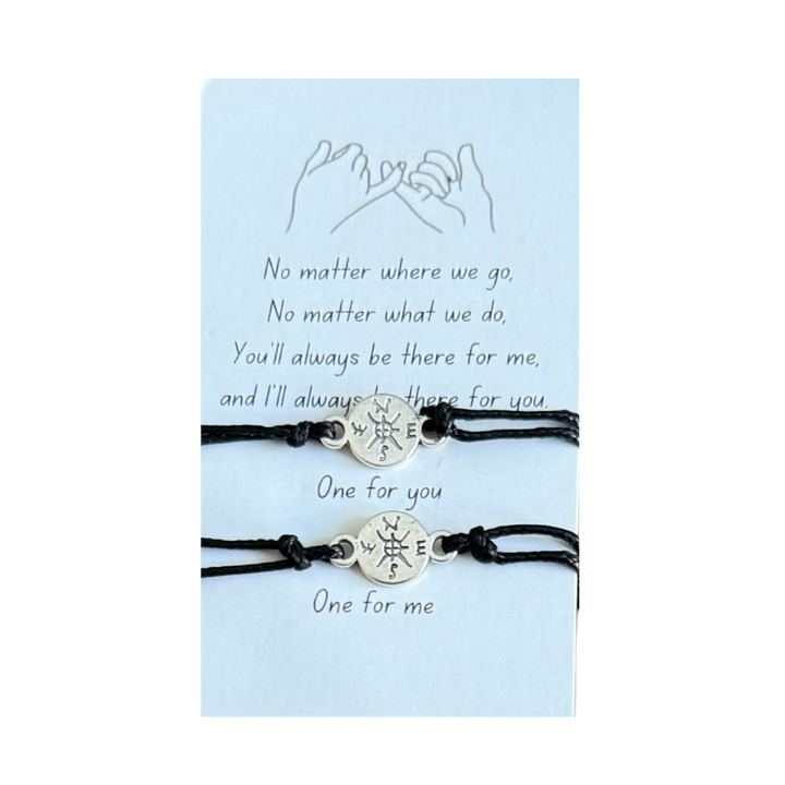 Two black bracelets with compass charms on a light blue card with text.